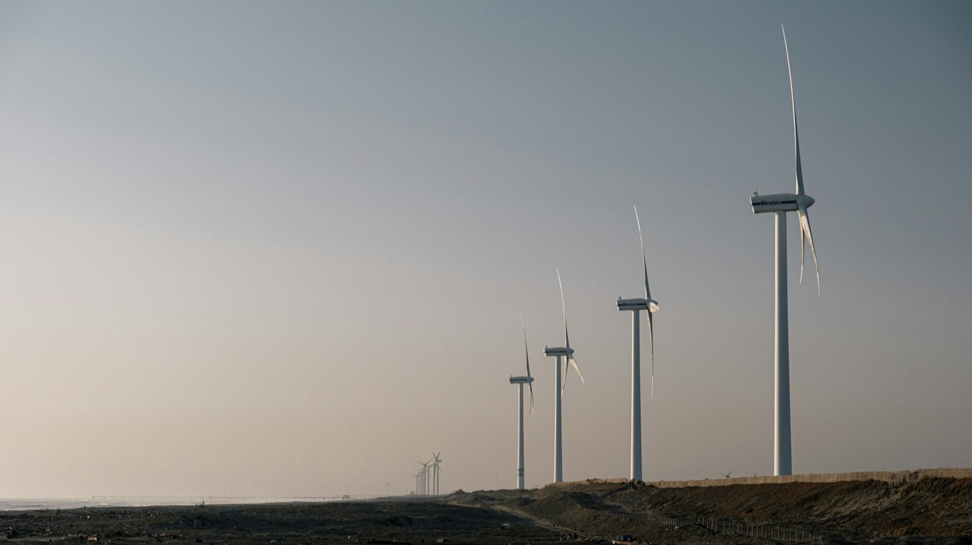 A row of wind turbines on flat land under a hazy sky